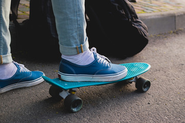 Man in blue skate shoes skateboarding in the park. Side view. The concept of city travelling,...