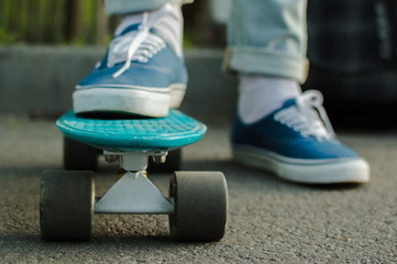 Man in blue skate shoes skateboarding in the park. Front view. The concept of city travelling,...