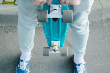 Perspective view of the man holding blue plastic penny skateboard. The concept of city travelling,...