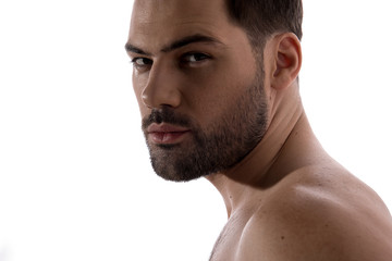 Obraz premium Beauty concept. Close up of face of pleasant shirtless bristled guy is standing and looking at camera thoughtfully. Isolated on light background