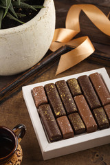 Set of luxury chocolate candies with golden splashes in box on wooden background