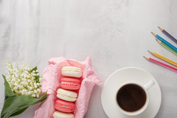 Flatlay with flowers and macaroons, and colored pencils with a blank space for an inscription on a light background. Can be used as a postcard for a holiday