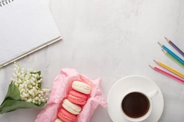 Flatlay with flowers and macaroons, and colored pencils with a blank space for an inscription on a light background. Can be used as a postcard for a holiday