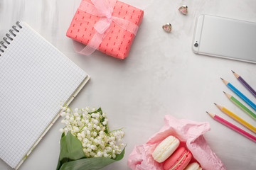 Flatlay with flowers and macaroons, and colored pencils, and a phone and a gift with a blank space for an inscription on a light background. Can be used as a postcard for a holiday