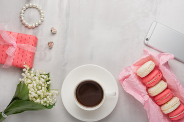Flatlay with flowers and macaroons, and a phone and a gift with a blank space for an inscription on a light background. Can be used as a postcard for a holiday