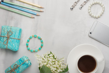 Flatlay with flowers and coffee, telephone and women's ornaments and gifts with an empty place for writing on a light background. Can be used as a postcard for a holiday
