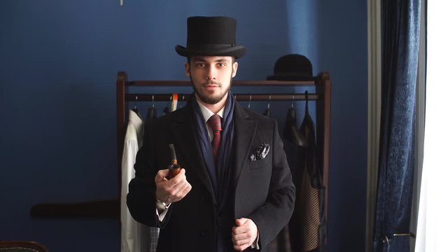 Portrait of attractive man in dark coat and trendy suit indoors tailors.