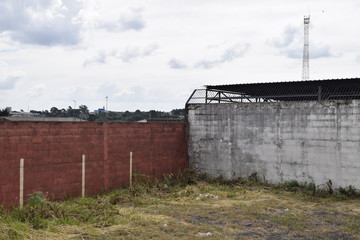 Fototapeta na wymiar Muro vermelho e branco em terreno abandonado