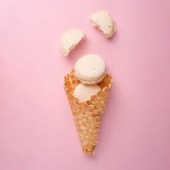 Flat-lay sweet cone wafers with white macaroons on a pastel light pink background, top view. The concept of spring or summer mood