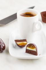 Cut handmade bonbon with ganache and fruit confiture filling with cup of coffee