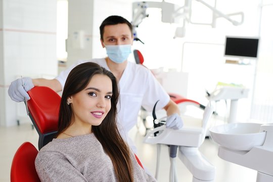 Young doctor with dentist and beautiful girl patient smiling looking at camera. Tooth whitening
