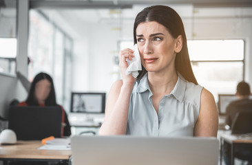 Portrait of young weeping girl facing problems while working in modern office. Trouble at job concept