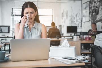 Obraz premium Portrait of crying female wiping away tears with tissue paper while looking at notebook computer. Unhappy worker concept