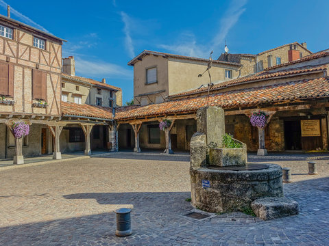 Revel, Midi Pyrenees, France - August 5, 2017: Medieval square with stone fountain and wooden arcades with flowers