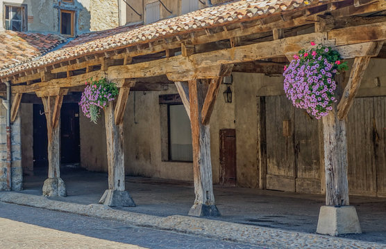 Revel, Midi Pyrenees, France - August 5, 2017: Arcade and wooden columns in medieval square with flowers