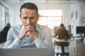 Portrait of worried businessman biting hand while using appliance during labor. Bad day in company concept