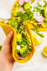 Vegan turmeric tacos with radish, broccoli and guacamole in hand. Healthy vegan food concept.