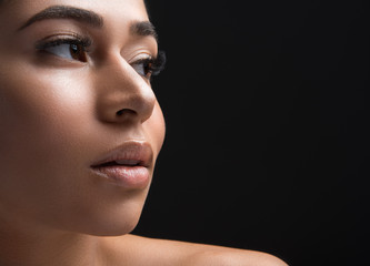 Fototapeta premium Close up of woman appearance with long eyelashes looking aside. Copy space in right side. Isolated on black background