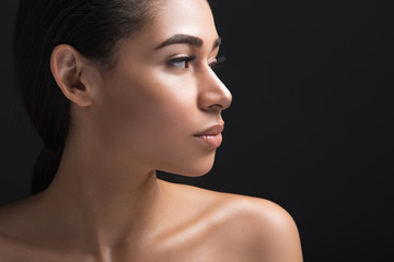 Fototapeta premium Close up of calm woman showing beautiful profile of her face. Copy space in right side. Isolated on black background