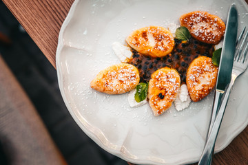 Cottage cheese pancakes from above served on a white plate. Wooden table. Food photography concept. Horizontal