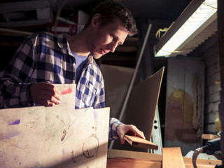 portrait of bearded man working with plywood in the dark room