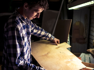portrait of bearded man working with plywood in the dark room