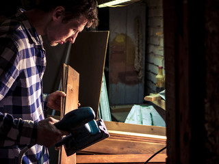 bearded young carpeter working in the workshop with wooden material