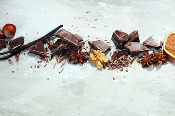 dark chocolate bars  with anise and nutson stone table and broken pieces of cocoa