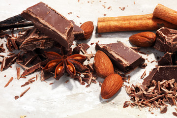 dark chocolate bars  with anise and nutson stone table and broken pieces of cocoa