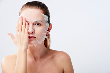 Young woman with sheet mask on her face