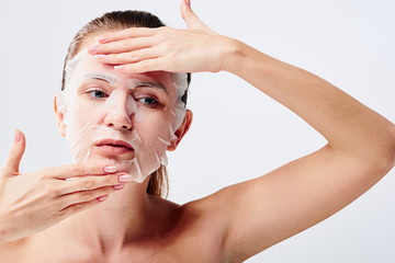 Young woman with sheet mask on her face