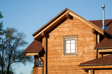 Part of modern wooden country house with blue sky on background. Roof of eco residential building near forest. Building and architecture of rustic chalet