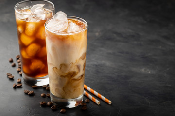 Ice coffee in a tall glass with cream poured over, brown sugar and coffee beans. Cold summer drink...