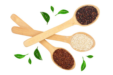 Black red white quinoa seeds in wooden spoon decorated with green leaves isolated on white background. Top view