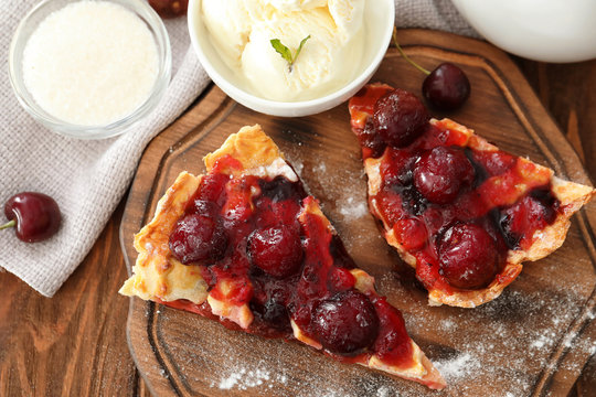 Delicious pieces of cherry pie and ice cream on wooden board