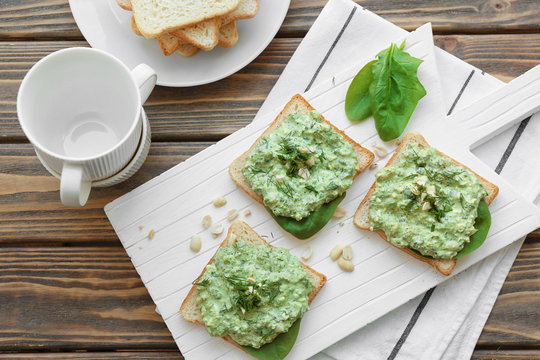 Toasts with tasty spinach sauce on table
