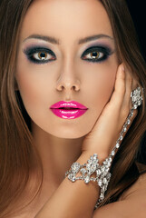 beautiful young girl with make-up of glossy pink lips with long eyelashes and a jewelry bracelet with stones on her hand