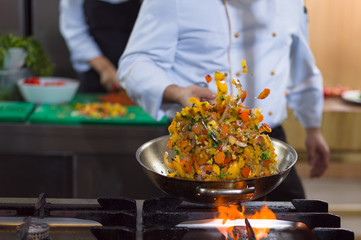 chef flipping vegetables in wok