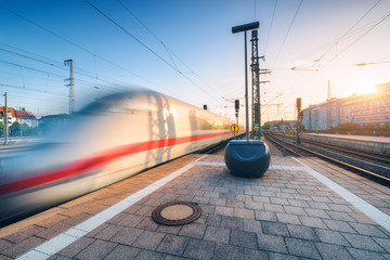 White high speed train in motion on the railway station at sunset. Germany. Blurred modern...