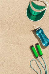 top view of arranged cap, water bottle and jump rope on sand