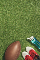 flat lay with sneakers, rugby ball and water bottle on green lawn