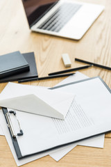 selective focus of notepad, notebooks and laptop on wooden tabletop