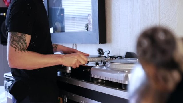 Mix and scratch, hands of a DJ on vinyl and mixer knobs. Close up of hands of DJ plays music mixing and scratching on turntable music equipment.