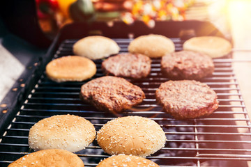 Bread and meat cooked for burgers outdoors on grill