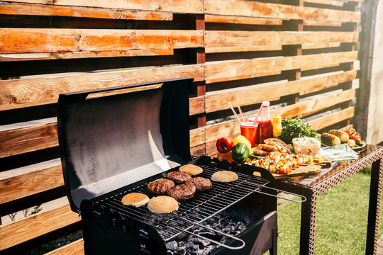 Seasonal vegetables and burgers cooked outdoors on grill