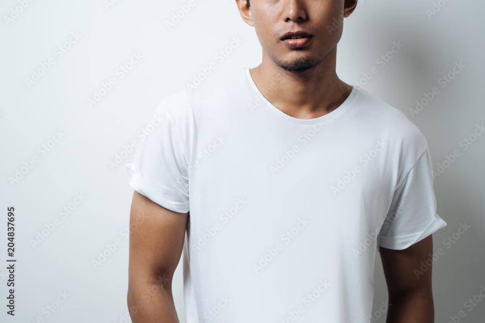 Wall mural Young guy wearing white blank t-shirt, empty wall, horizontal studio close-up