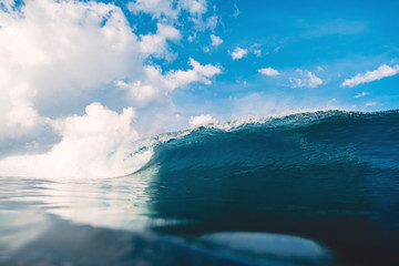 Blue barrel wave in ocean. Breaking wave and sky with clouds in Bali