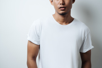 Obraz premium Young guy wearing white blank t-shirt, empty wall, horizontal studio close-up