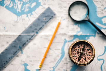 top view of vintage compass with ruler and magnifying glass on map