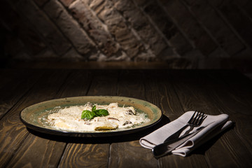 close up view of italian dish with cutlery on napkin on wooden surface